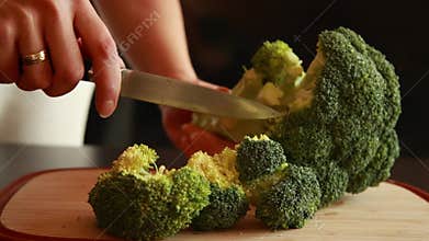 Slicing Broccoli Head into Florets on Wooden Board