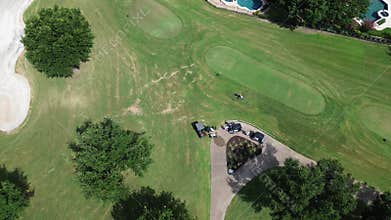 Golfers and caddie walking out of grassy golf course to club cars, dumping the cooler leaving upscale country club situated in