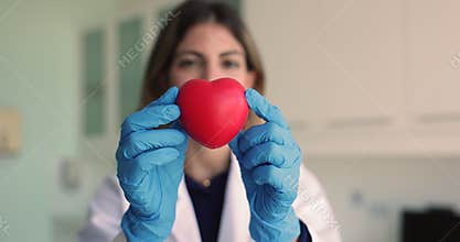 Cardiologist showing to camera red heart, close up
