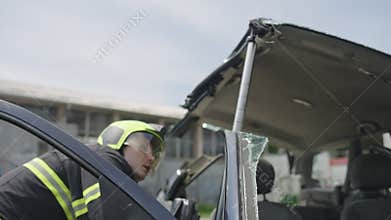 A courageous firefighter, equipped with specialized tools, heroically rescues people trapped in a car accident