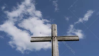 Wooden cross stands against a blue sky
