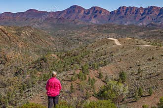 Woman tourist looks at semi arid valley and magnificent mountain range.