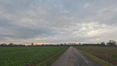 Car ride to the horizon between fields and meadows and clouds