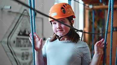 A little overweight girl is fat during an extreme workout in a rope park indoors