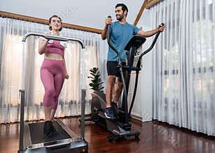 Athletic and sporty couple running on elliptical running machine at gaiety home.