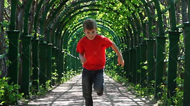 boy in red shirt runs through arched corridor