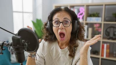 Middle age hispanic woman\'s shocked reaction at radio studio, surprise, fear, amazement captured on face indoor! behind the