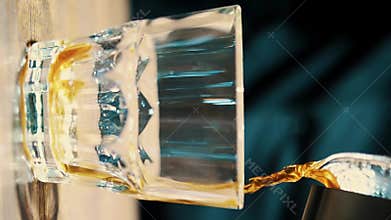 Pouring freshly brewed coffee from glass teapot into a serving glass beaker.