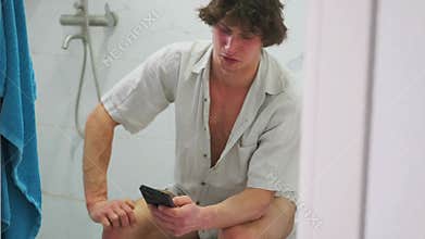 Joyful restroom selfie, Laughing man using toilet phone, Relaxed individual enjoying humorous moment in bathroom, Amused man