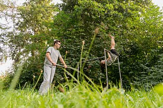 A father guides his child as they engage in playful activities at a playground. The child attempts to perform a handstand while