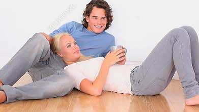 Happy couple on the floor with a cup
