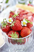Glass bowl of strawberries standing on rustic wooden table in th