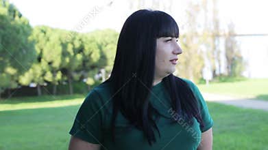Expressive woman with black hair talking outdoors in a park