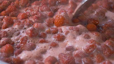 Boiling strawberries in large pot create steam as they turn into thick mixture