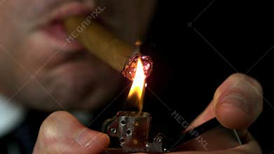 Businessman lighting his cigar on black background