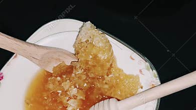 Detailed exploration of raw honeycomb golden honey with utensils
