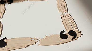 A square frame formed by four beige arms with hands at the corners on a pale surface
