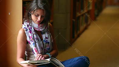 Student reading a book sitting by a window