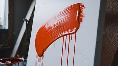 Close View of Red Paint Stroke Drying on a White Canvas in a Studio