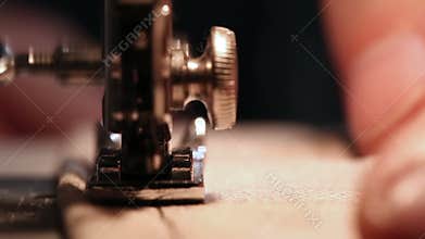 Male sewer working with fabric and thread on sewing machine