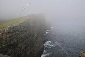 Cliffs covered by fog on Island Vágar of the Faroe Islands