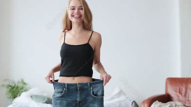 Woman weight loss by wearing and old jeans