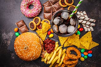 Junk food concept. Unhealthy food background. Fast food and sugar. Burger, sweets, chips, chocolate, donuts, soda, top view