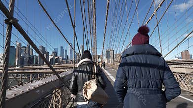 Two friends in New York walk over the famous Brooklyn Bridge