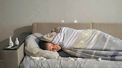 Sick man lying under blanket