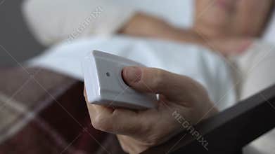 Elderly woman hardly breathing in bed, pushing call button, needing medical help