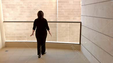 Claustrophobic woman stands on the balcony with a hell of a view