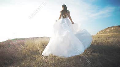 Running bride in amazing long dress through the landscape.
