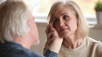 Loving senior husband stroking face of aged wife confessing love