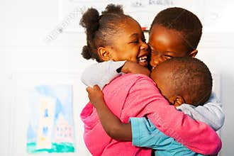 Three hugging close black kids in nursery class