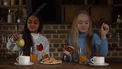 Excited little girls relaxing together in kitchen