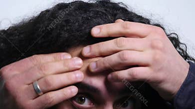 Young man squeezing a pimple on white background. close up