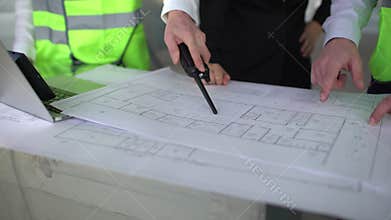 Close up hands of three workers or engineers discussing building drawings in office. Closeup shooting of arms moving
