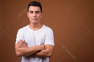 Young handsome Hispanic man against brown background