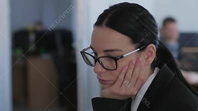 No ideas, unmotivated business woman with glasses thinks while working in office close-up