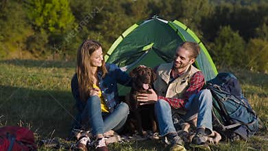 Man and woman traveling with dog at camp
