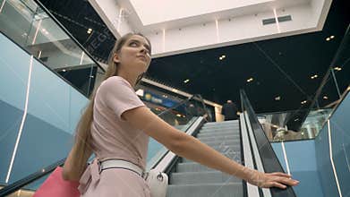 Young attractive girls standing on escalator in mall, holding bags, shopping concept, fashion concept