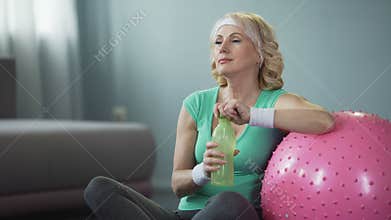 Beautiful middle-aged athlete drinking water after workout, healthy lifestyle