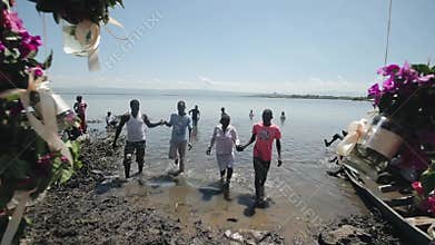 KENYA, KISUMU - MAY 20, 2017: African people go out of the water on the lake shore on a sunny summer day.