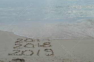 Happy New Years 2017, 2018 and 2019 handwritten on sand