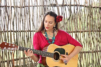 Beautiful woman with a guitar and a red rose in her hair