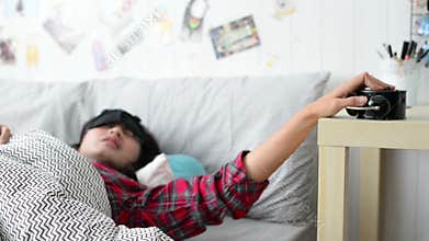 Young woman is sleeping in the morning when ring the alarm switch off it and continue sleeping