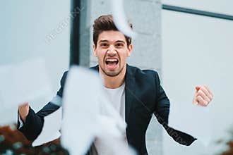 Angry furious male office worker throwing crumpled paper, having nervous breakdown at work, screaming in anger, stress
