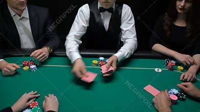 Casino dealer shuffling and distributing cards, players checking combination