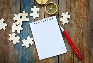 Purposes, goals and strategy building concept. Empty paper notepad, compass navigation, puzzles and pen