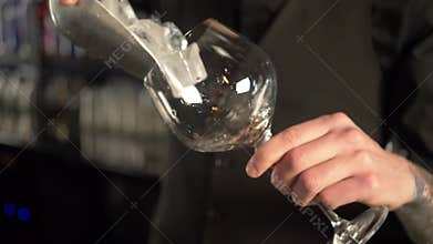 Barman pour ice cubes into cocktail glass